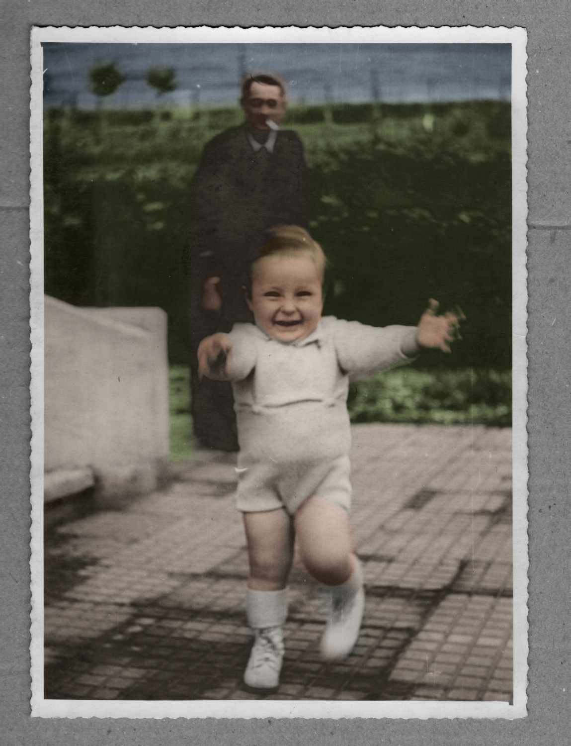 Gérard, 21 mois, Bitche, 1939 — essai de colorisation : tricot crème, haie verte, dallage beige